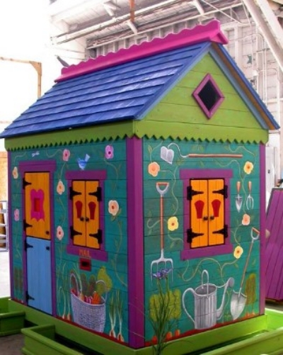 A whimsical painted garden shed in bright blue, green, and orange