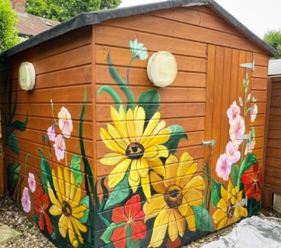 Brown garden shed with vibrant painted large flowers