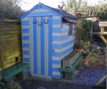 garden shed with bright blue stripes on it and horse shoe face.